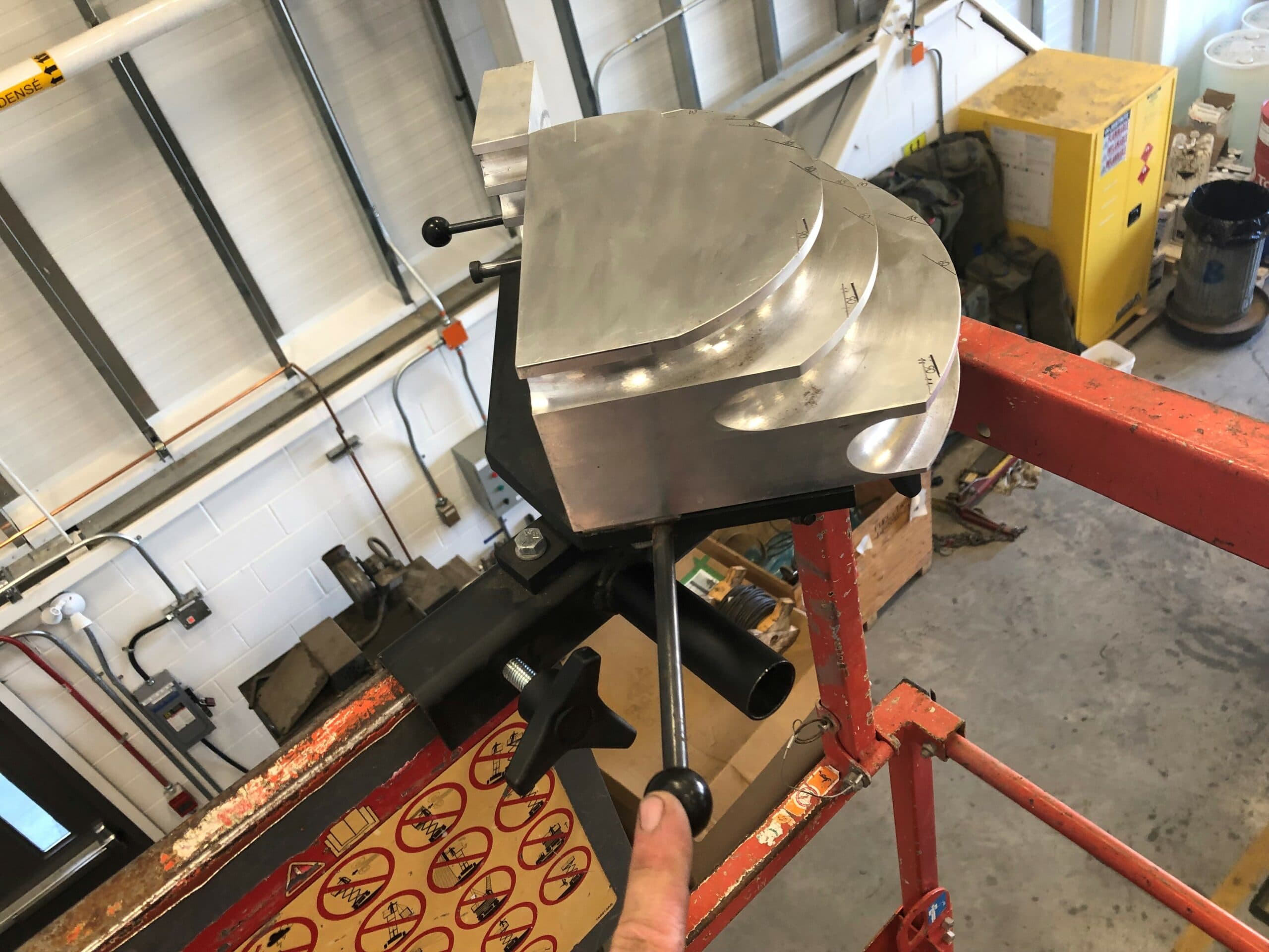 The rotation handle of a skybender emt conduit bender being used to rotate the tool while attached to the guardrail on a scissor lift.