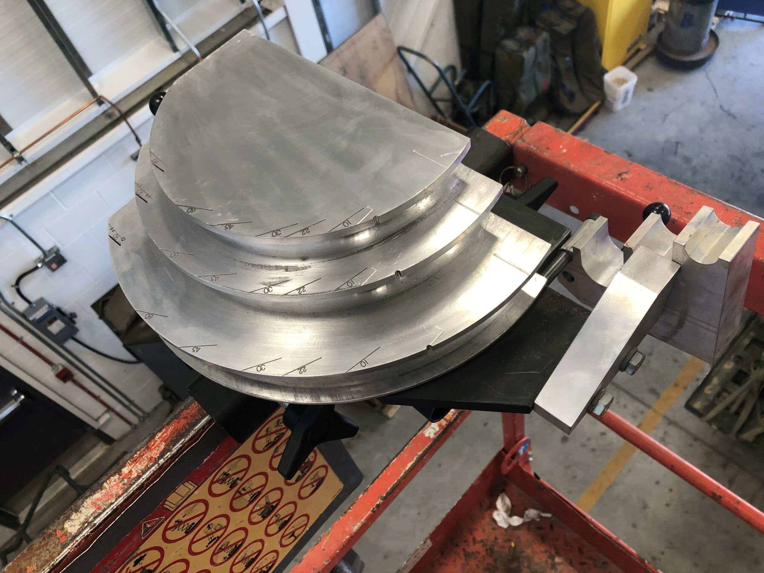 Skybender lift-mounted conduit bender. The conduit bender is mounted to the guardrail of a lift. On the top of the tool are angle marks.