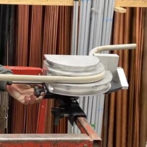 the rack-a-tiers skybender emt bender attached to the guardrail of a scissor lift. the tool is being used to bend 1 inch EMT